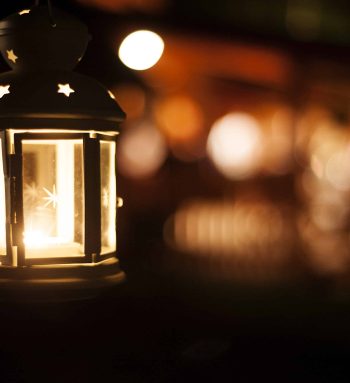 Decorative metal lantern lit by a glowing candle in night