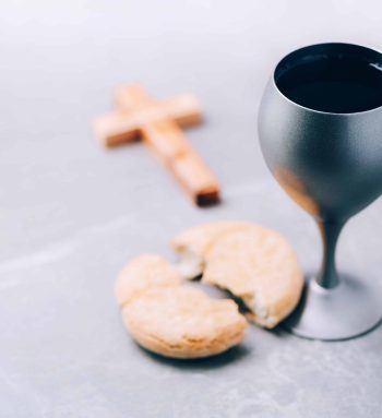 Unleavened bread, chalice of wine, wooden cross on grey background. Christian communion for reminder of Jesus sacrifice. Easter passover. Eucharist concept. Christianity symbol and faith.